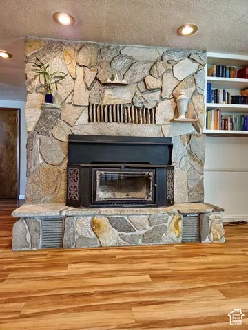 Floor-to-ceiling stone fireplace featuring a dark-toned wood-burning insert