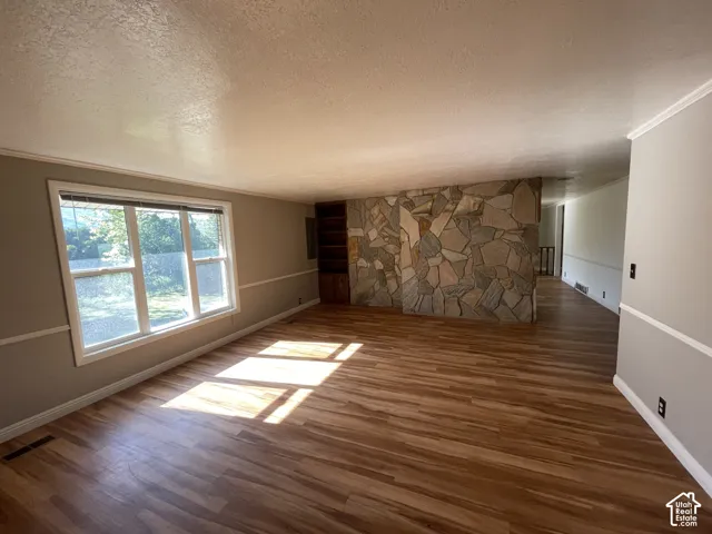 Spacious interior featuring wood-finish flooring, a stone-accented wall, and built-in shelving
