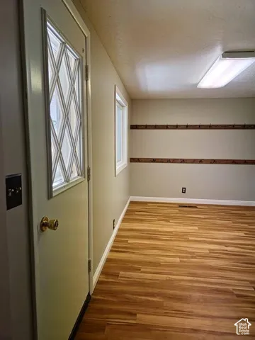 Entryway featuring a decorative glass-paned door, wood-finish flooring, and built-in wall hooks