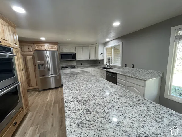 Spacious kitchen featuring extensive granite countertops, light wood-finish flooring, and recessed lighting