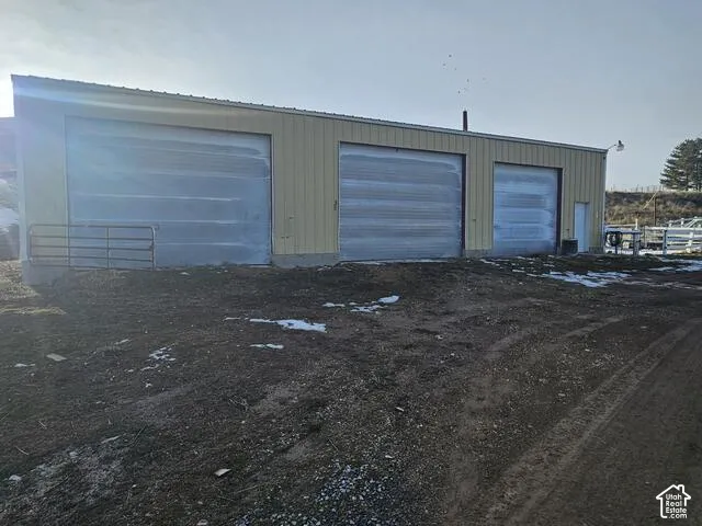 Metal-sided utility building featuring three roll-up doors, a pedestrian entry door, and a full-length gutter system