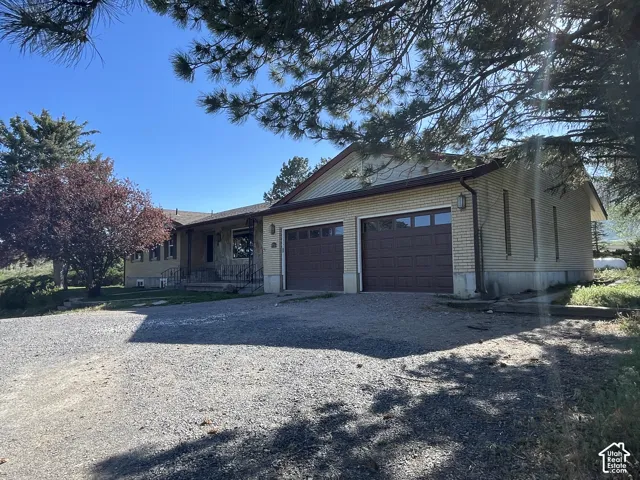 Ranch-style residence featuring a two-car attached garage with individual brown panel doors and a light brick exterior