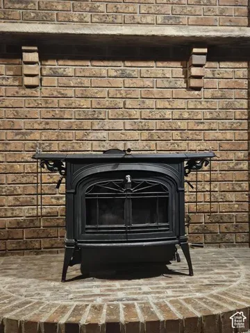 Cast iron wood-burning stove with intricate detailing, set against a full brick wall with a stone mantel