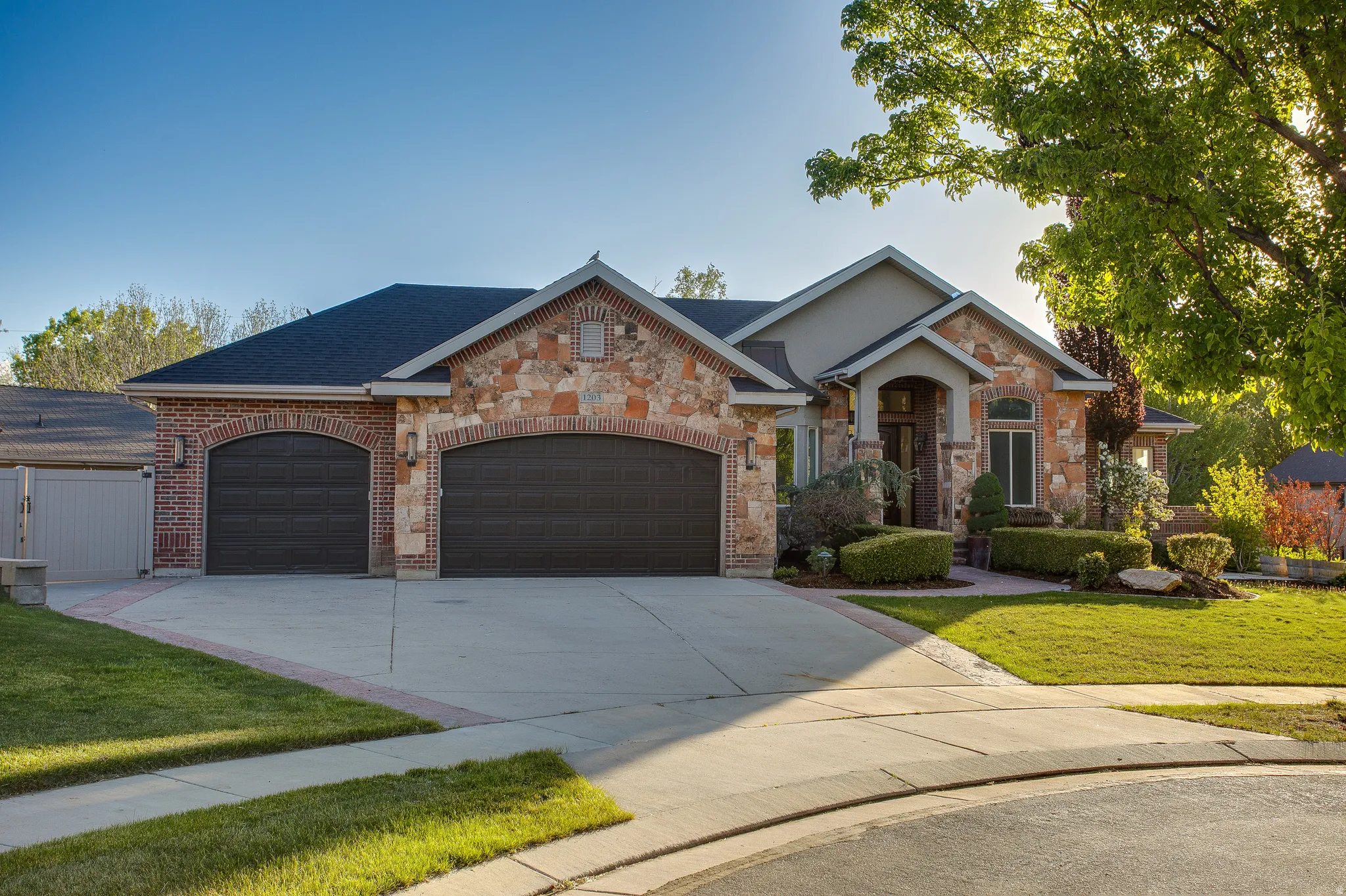 Stone and brick facade residence featuring an arched portico entry