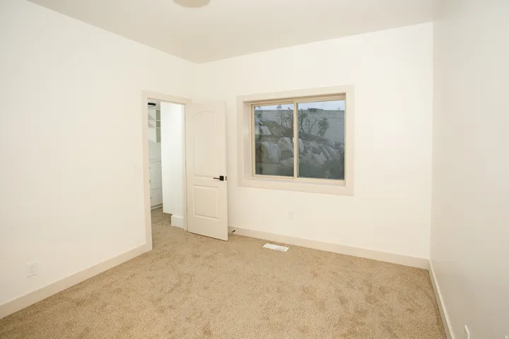 Neutral-toned room featuring light beige carpeting and white painted walls