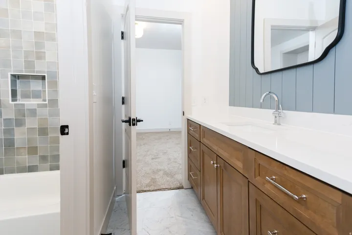 Bathroom featuring a wood-finish vanity with an integrated sink, white countertop, and chrome faucet