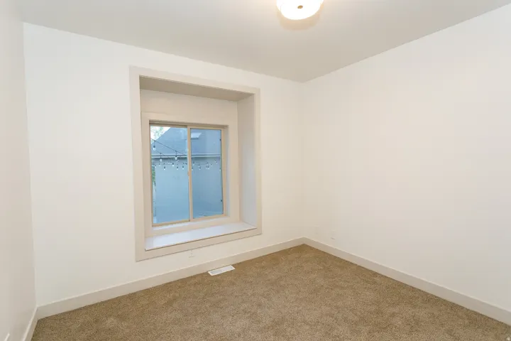 Recessed window with a deep sill, neutral wall paint, ceiling-mounted light fixture, and carpet flooring