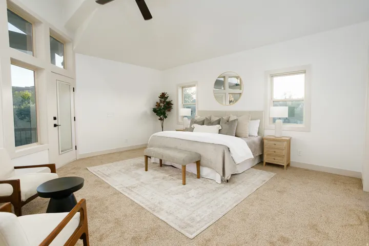 Carpeted bedroom with a vaulted ceiling and a ceiling fan