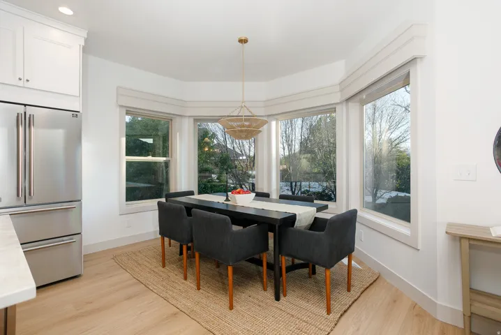 Dining area featuring a bay window, wood-finish flooring, and a contemporary chandelier
