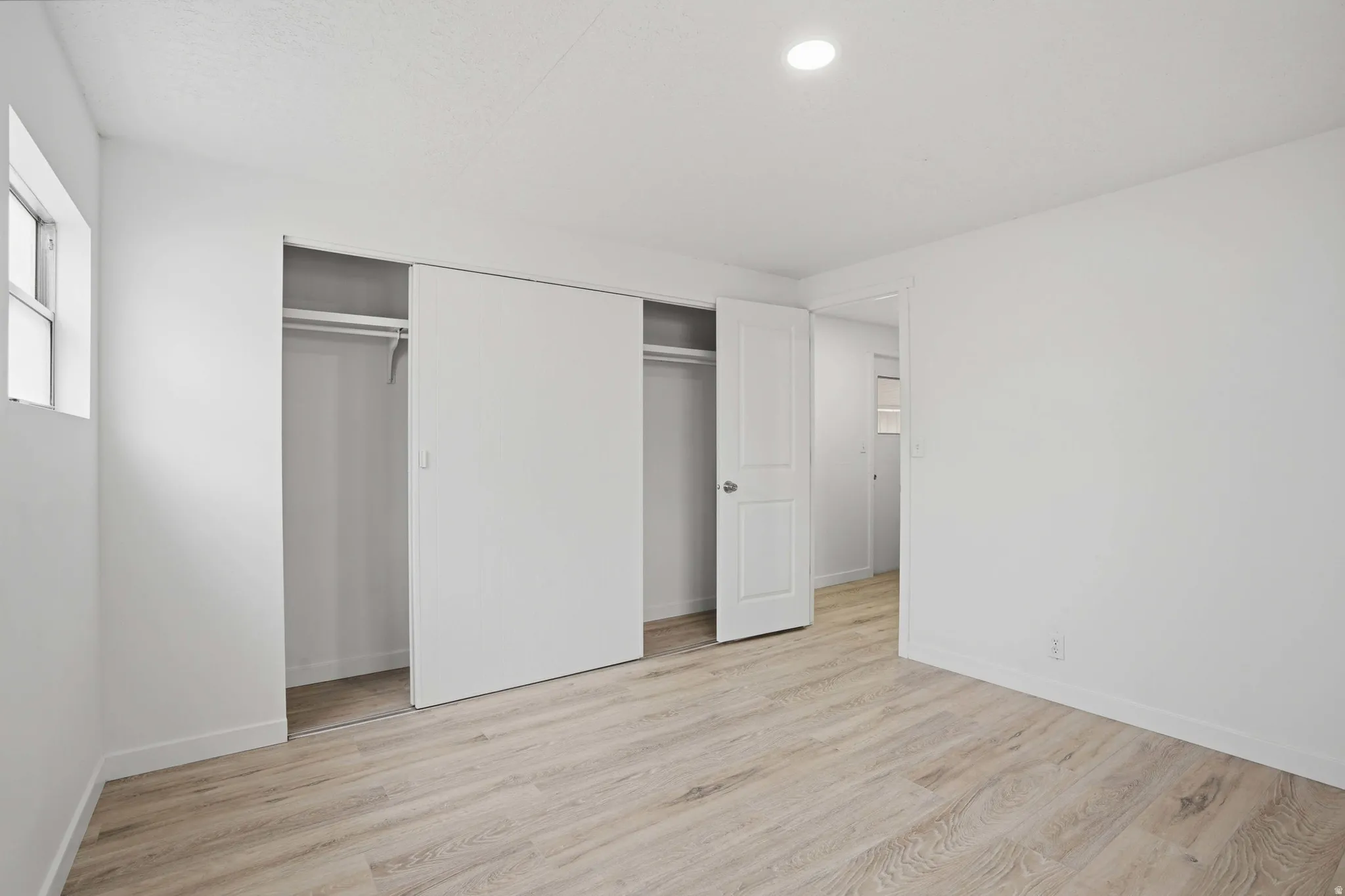 Neutral toned room featuring wood-finish flooring and white walls