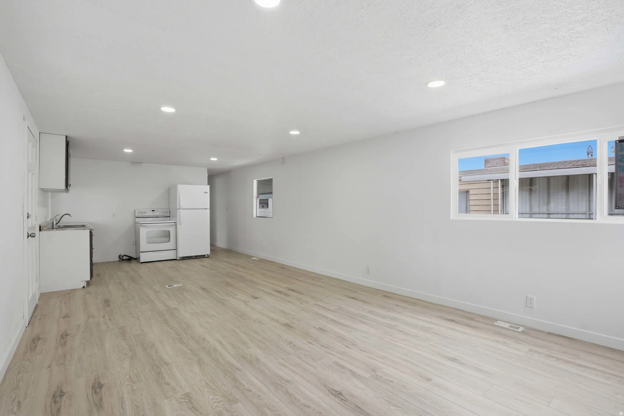 Open-concept living area featuring wood-finish flooring, recessed lighting, and white walls