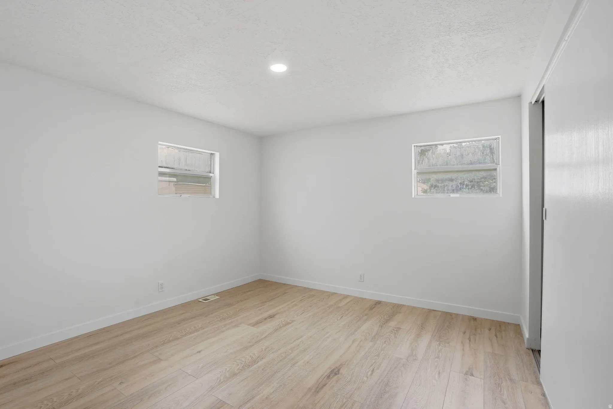 Bright room featuring wood-finish flooring and recessed lighting