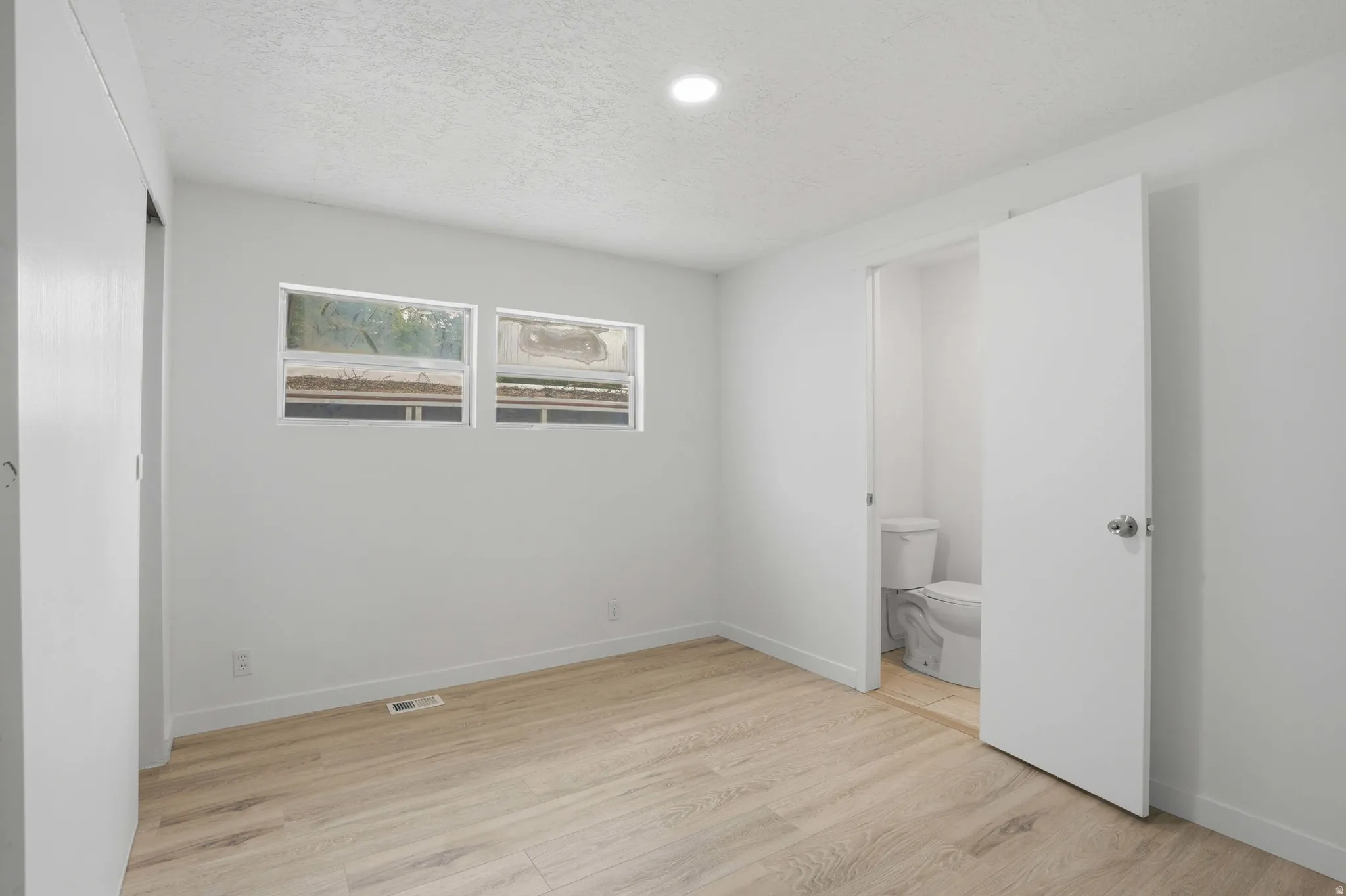Bright room with light wood-finish flooring and recessed lighting