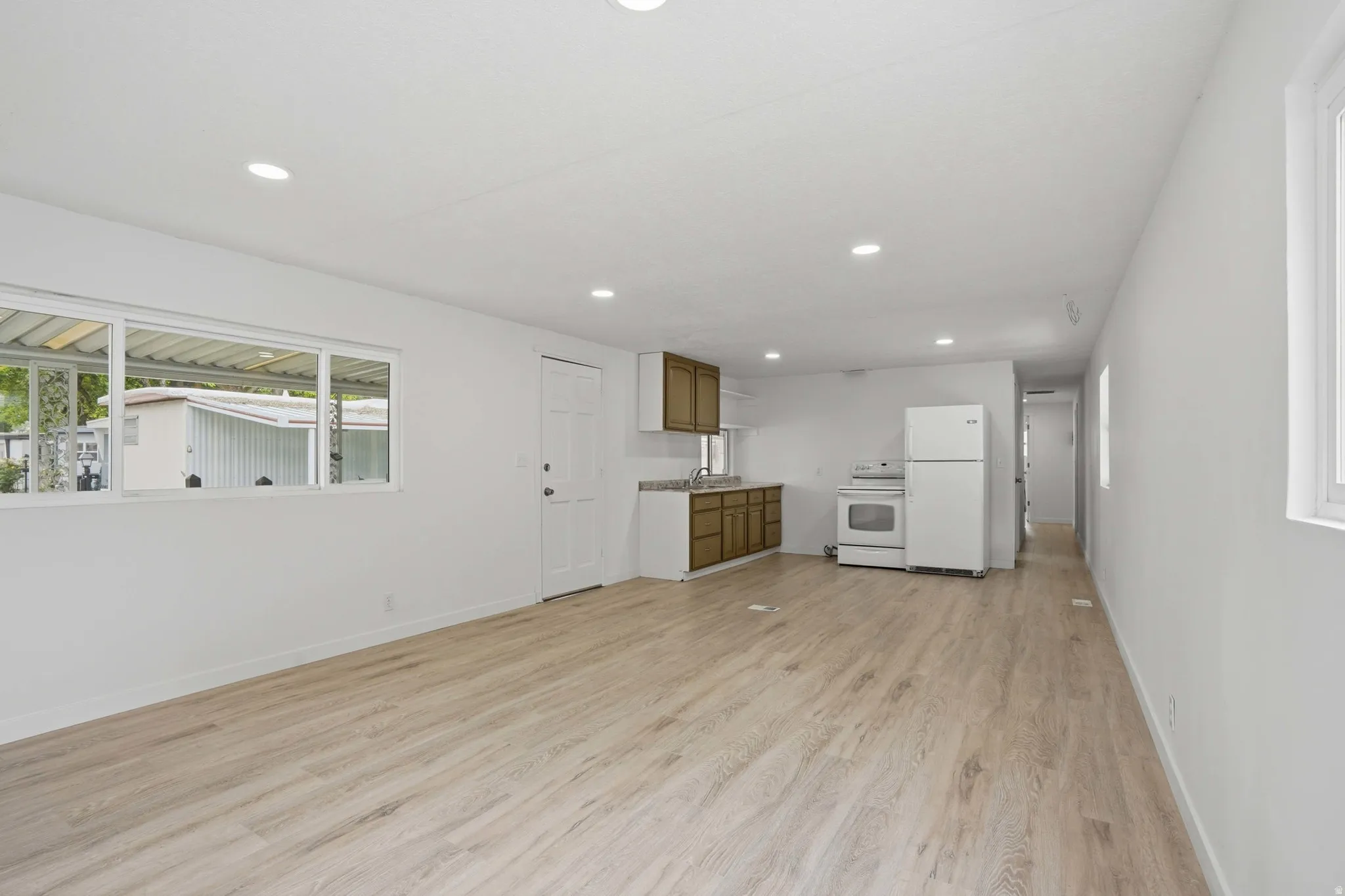 Open-concept living area featuring light wood-finish flooring, recessed lighting, and white walls