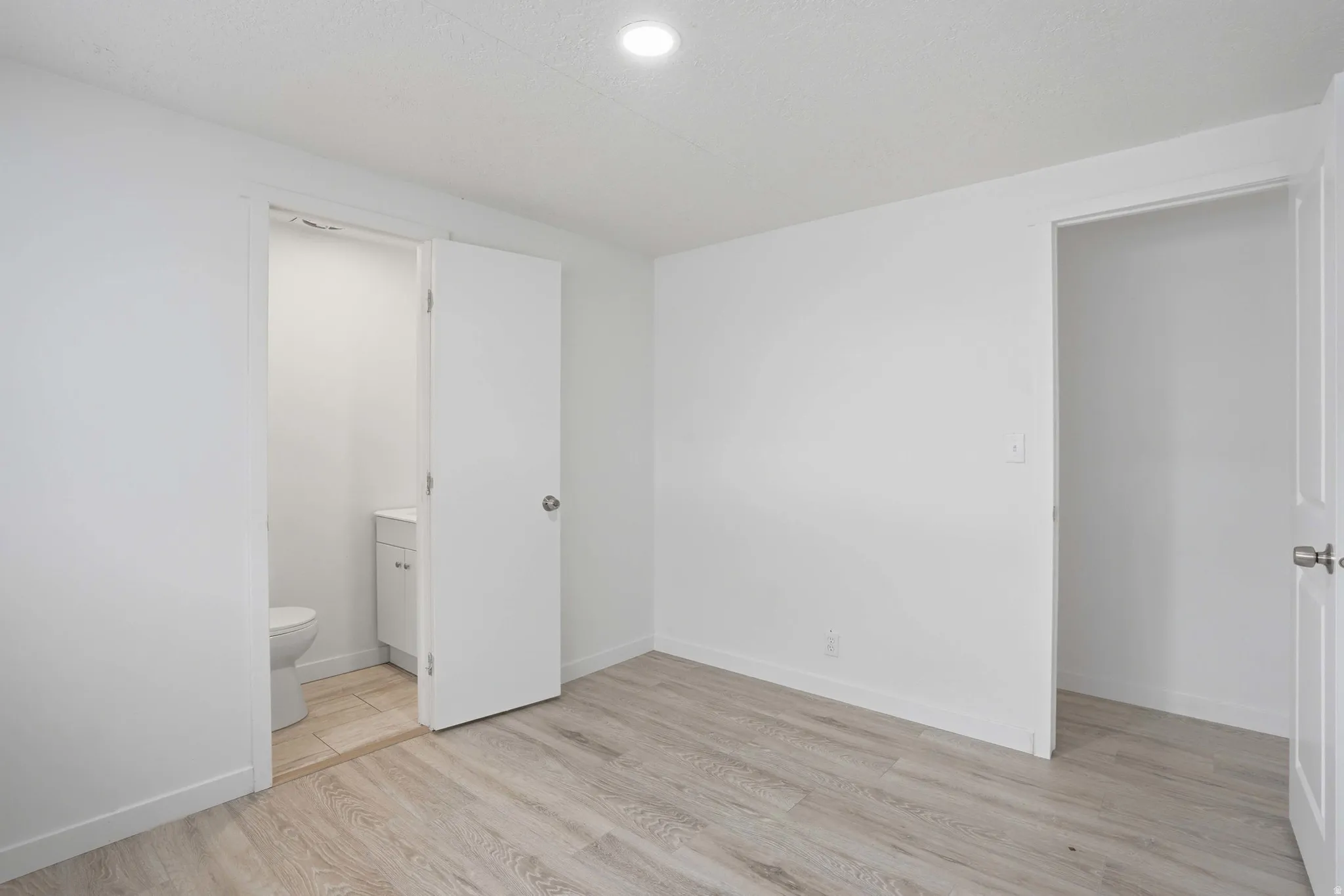 Light wood-finish flooring with white baseboards and walls