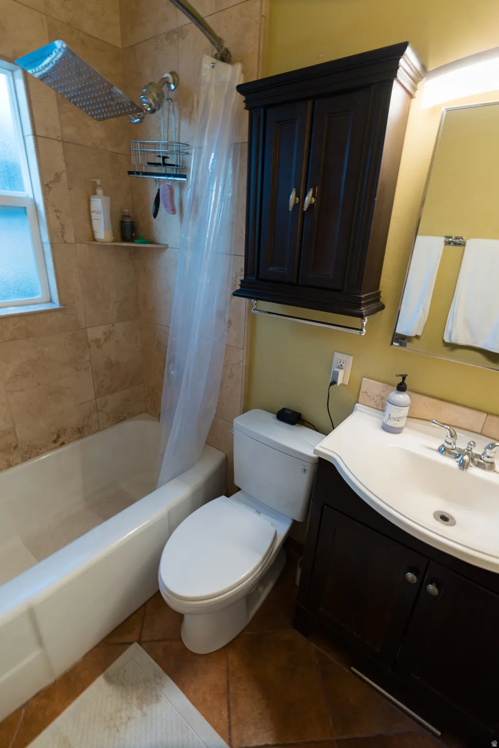 Full bath with vanity, shower / tub combo with curtain, and dark tile patterned floors