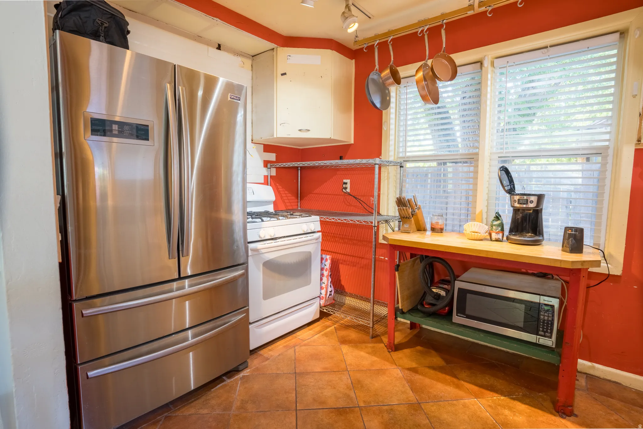 Kitchen with stainless steel appliances, light tile patterned floors, track lighting, and white cabinetry