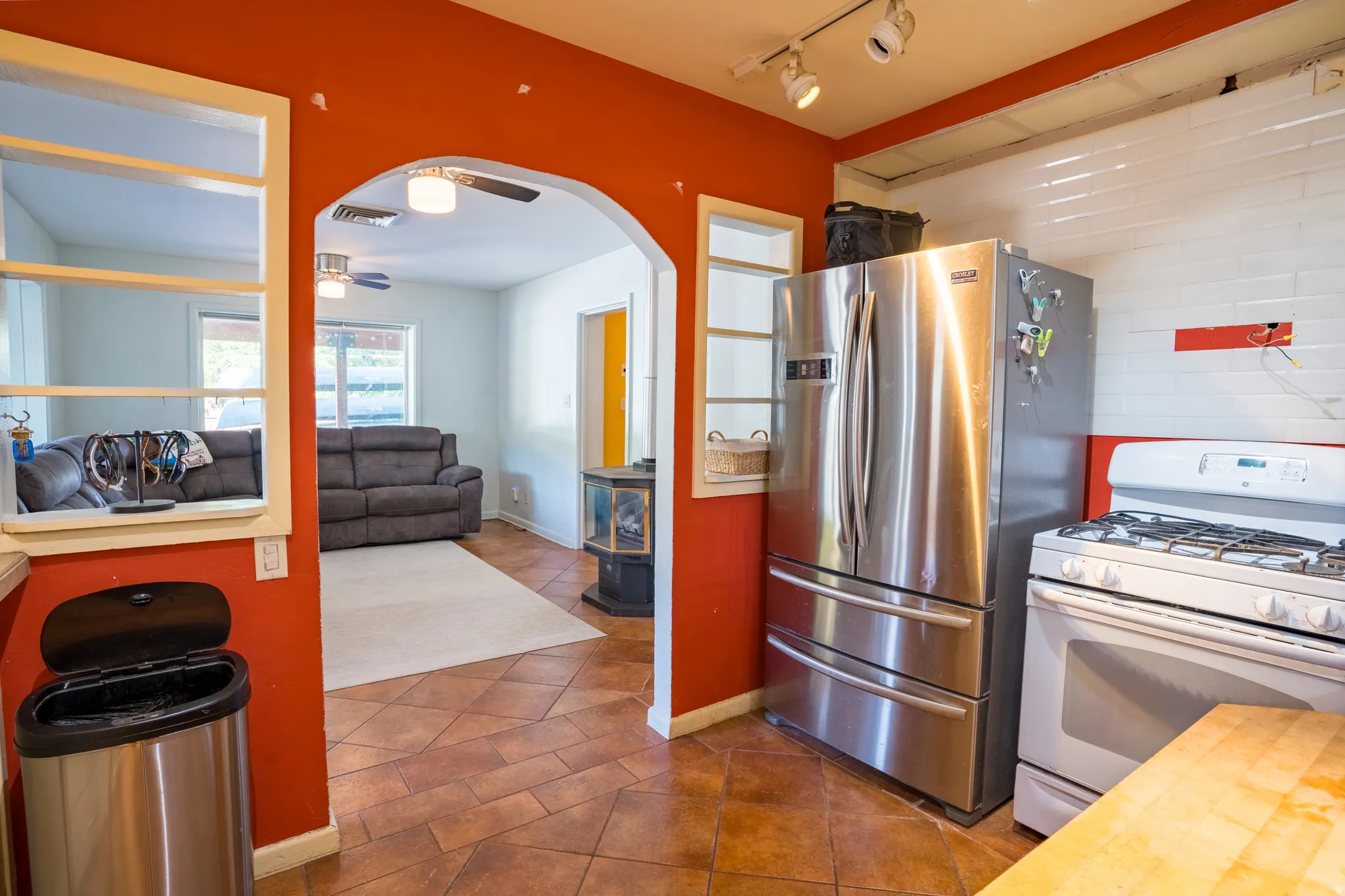 Kitchen with butcher block countertops, white gas range oven, freestanding refrigerator, ceiling fan, and dark tile patterned floors