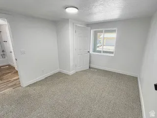 Carpeted room featuring a white interior door, a window with white trim, and a ceiling-mounted light fixture