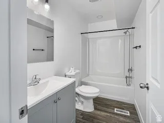 Full bathroom featuring wood-finish flooring, a white vanity with a rectangular sink, a coordinated mirror, and a shower-tub combination