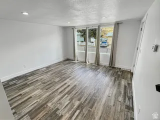 Spacious interior featuring wood-finish flooring, white walls, and recessed ceiling lighting