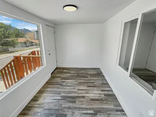 Interior space featuring wood-finish flooring, white walls, and a contemporary flush-mount ceiling light