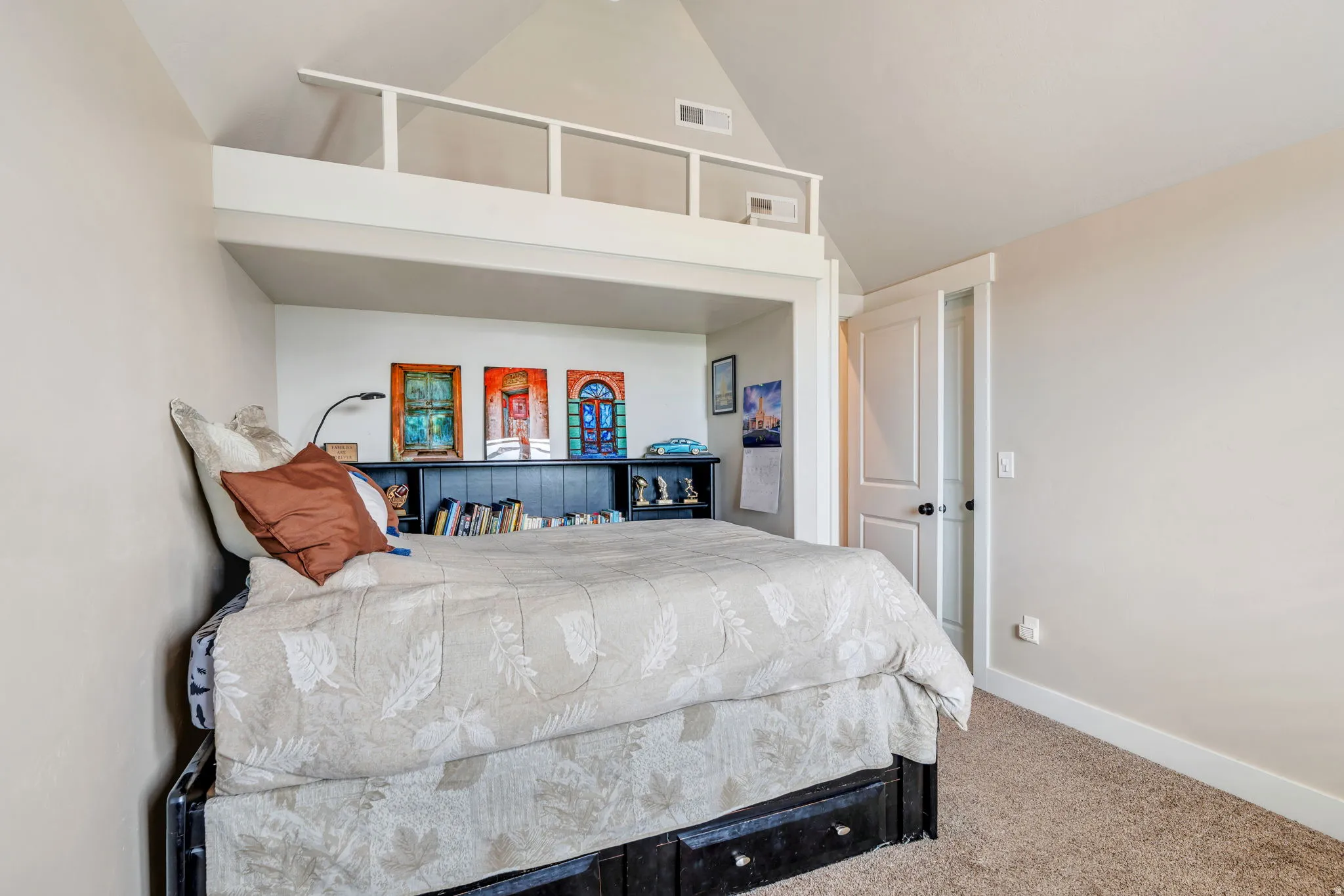 Bedroom featuring a built-in loft space with white railing, light beige wall paint, and a textured carpet