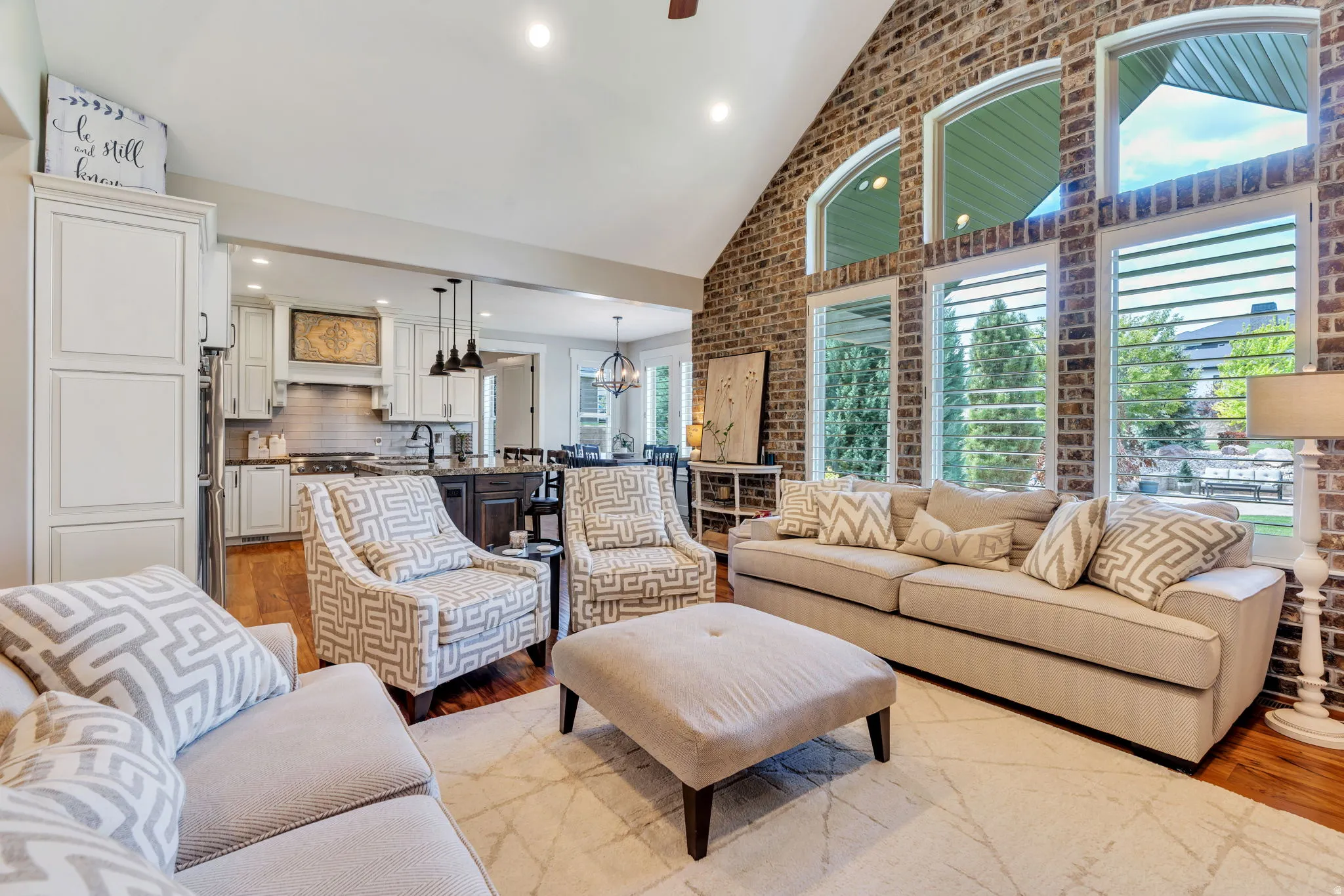Open-concept living space featuring a vaulted ceiling and exposed brick accent wall