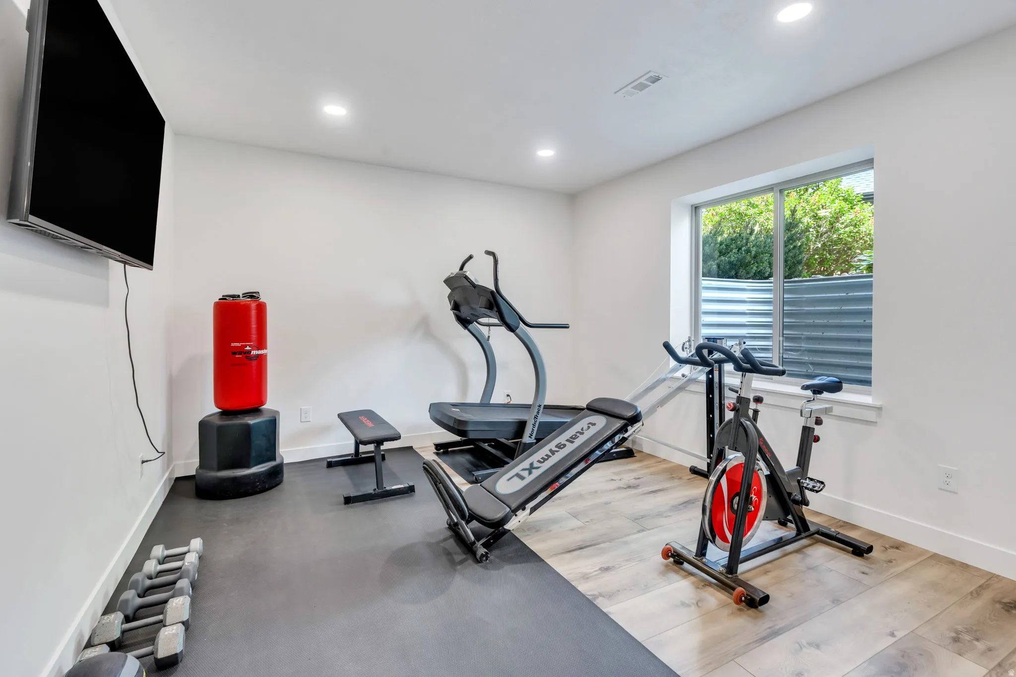 Dedicated fitness area with bright white walls and recessed lighting