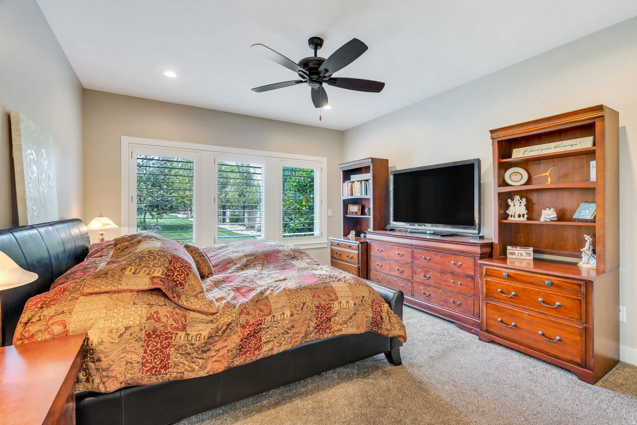 Carpeted room featuring a ceiling fan with light, recessed lighting, and multiple windows with plantation shutters