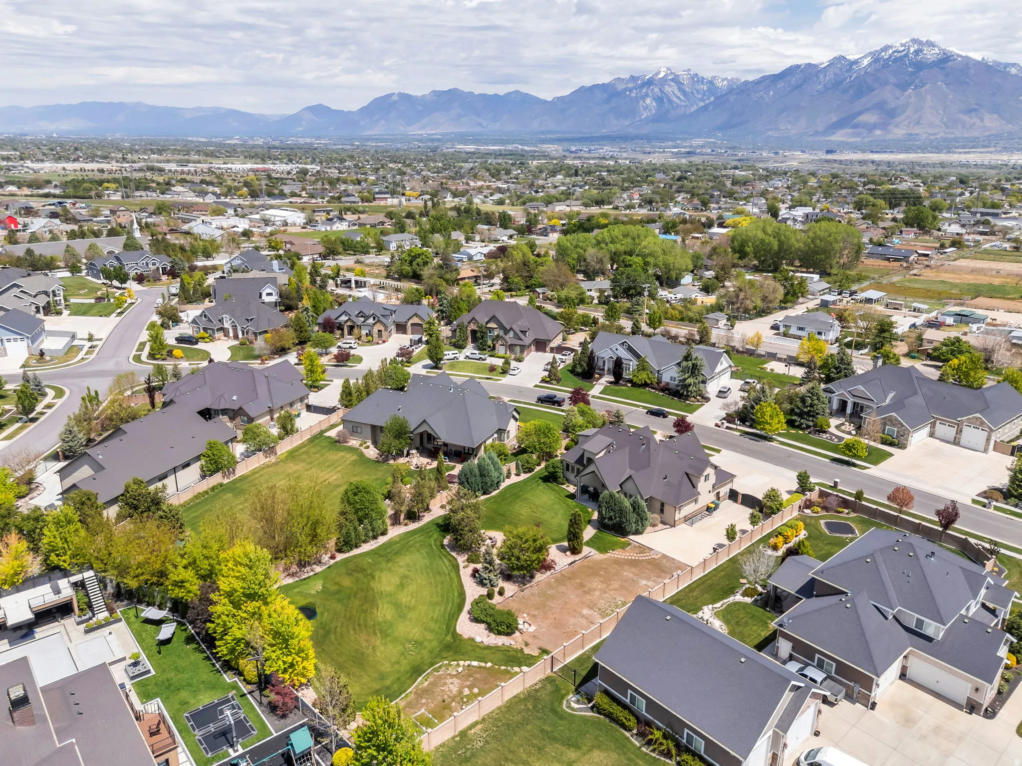 Expansive residential neighborhood featuring diverse architectural styles, mature landscaping, paved roadways, and mountain scenery