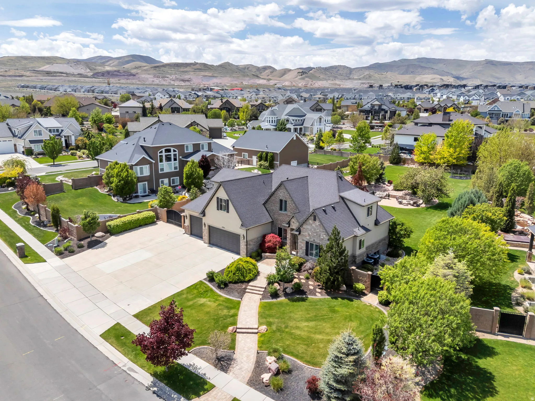 Expansive property featuring a stone and siding exterior, multi-car garage, mature landscaping, and a paver stone walkway