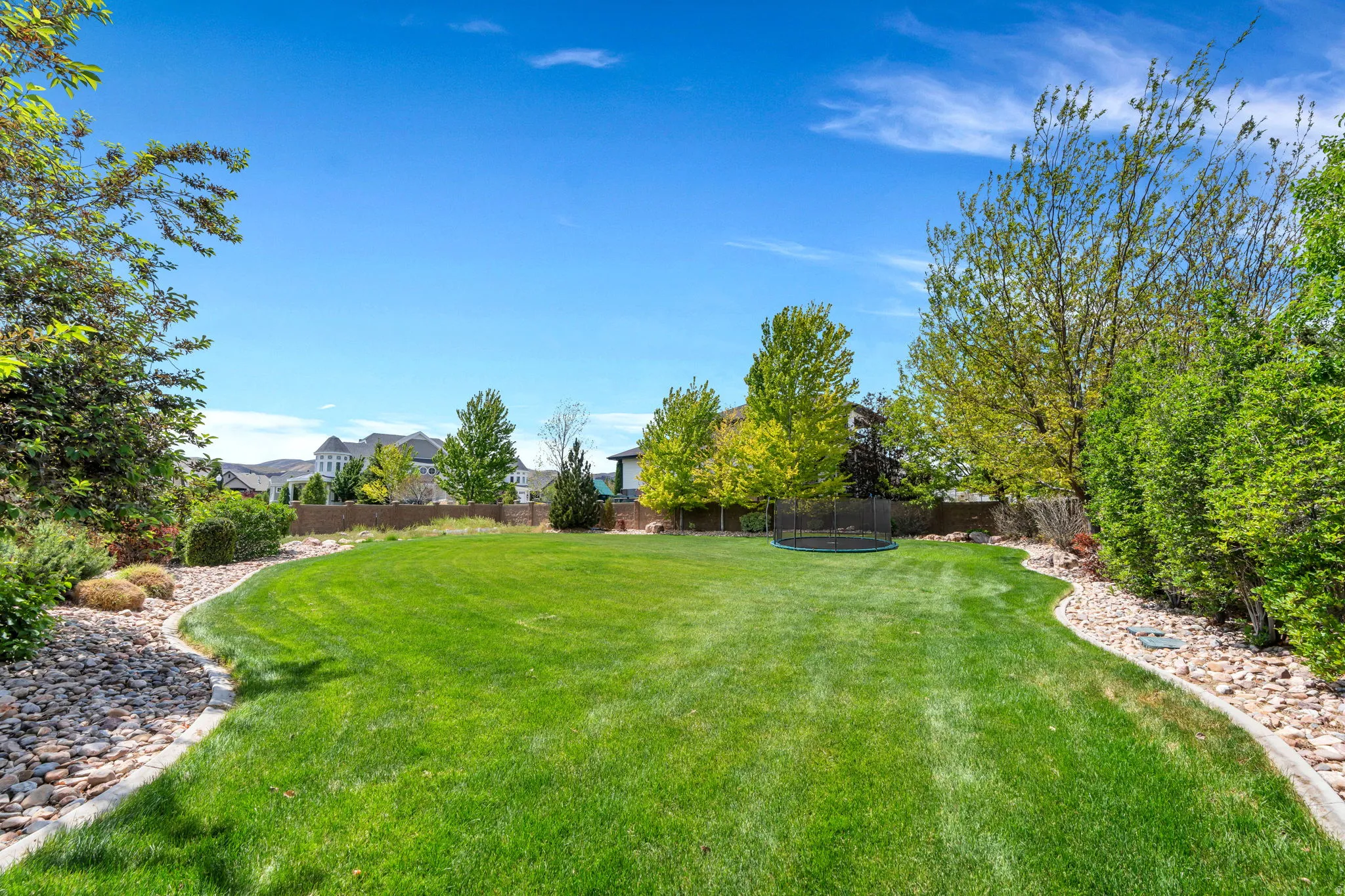 Expansive green lawn framed by mature trees and varied shrubbery
