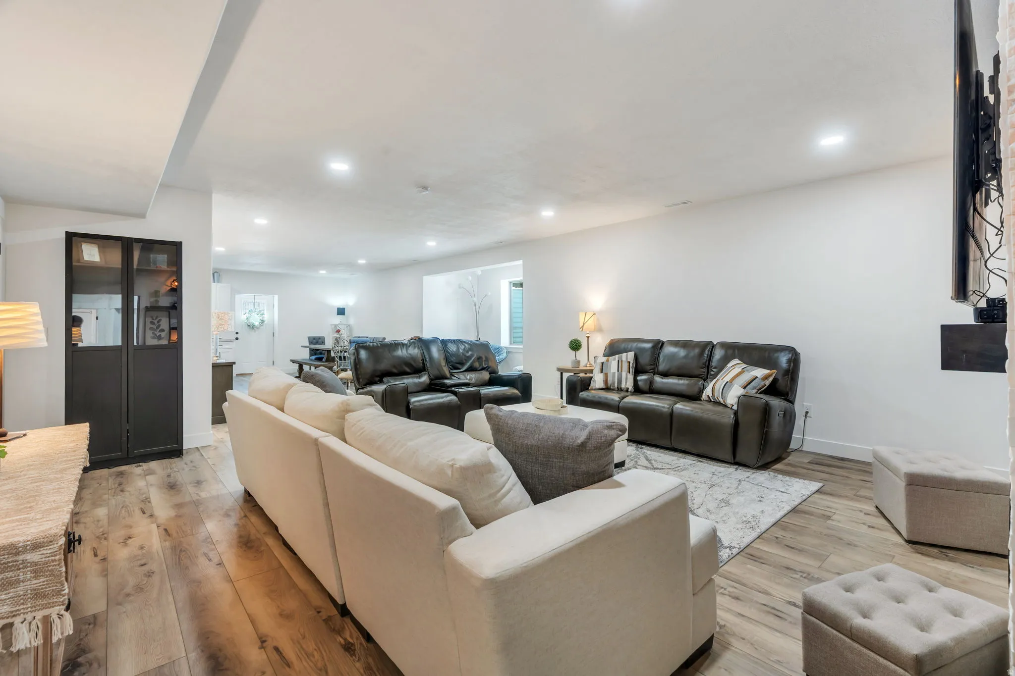 Spacious living area featuring wood-finish flooring, recessed lighting, and white walls