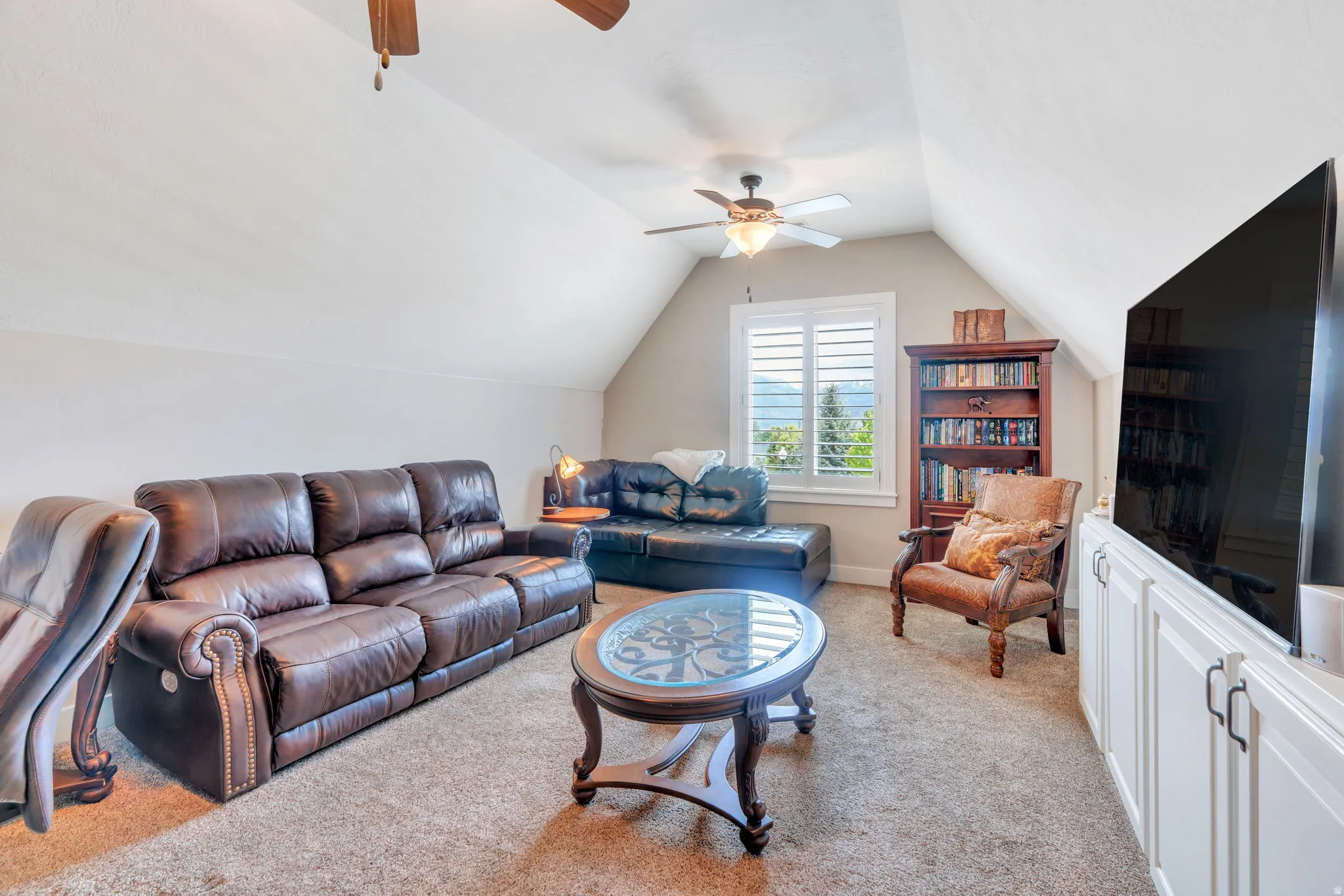 Carpeted bonus room featuring a vaulted ceiling and a ceiling fan