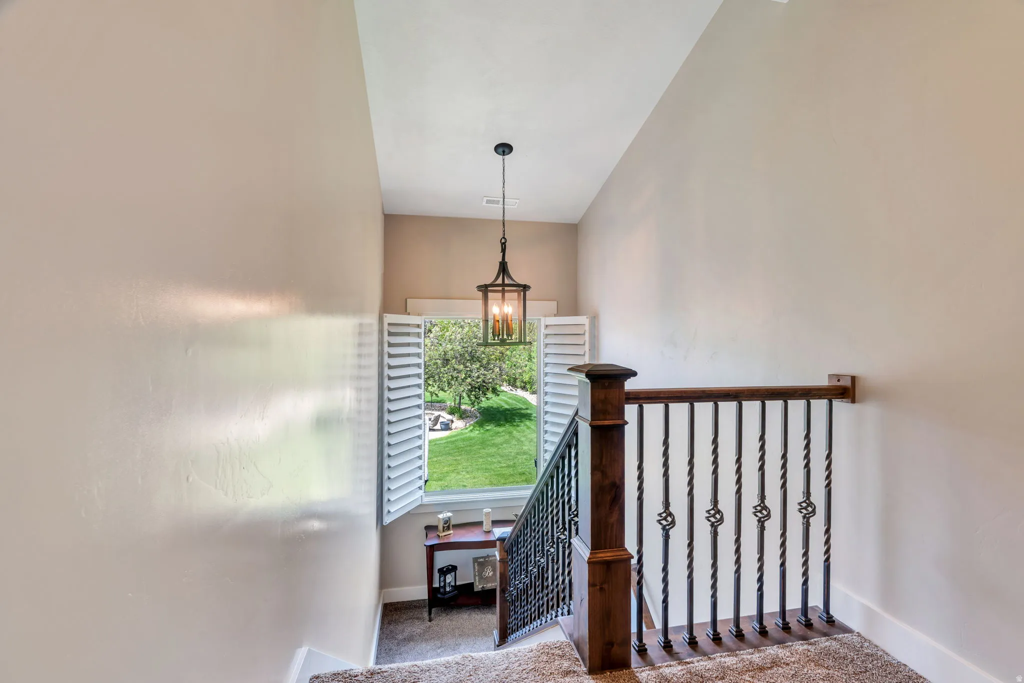 Staircase featuring dark wood newel posts, wrought iron balusters with twisted details, and a coordinating dark wood handrail
