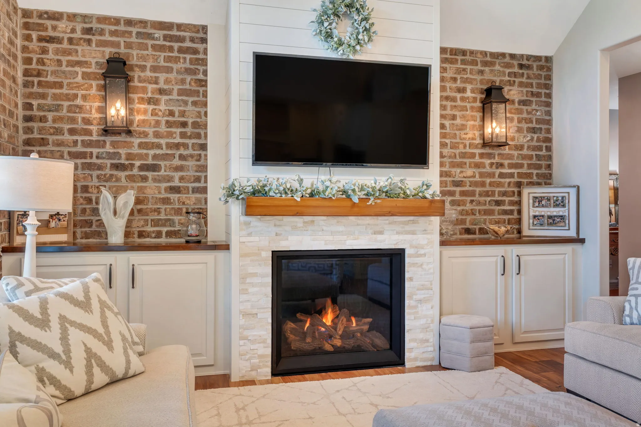 Central fireplace featuring a stacked stone surround, wood mantel, and shiplap accent wall