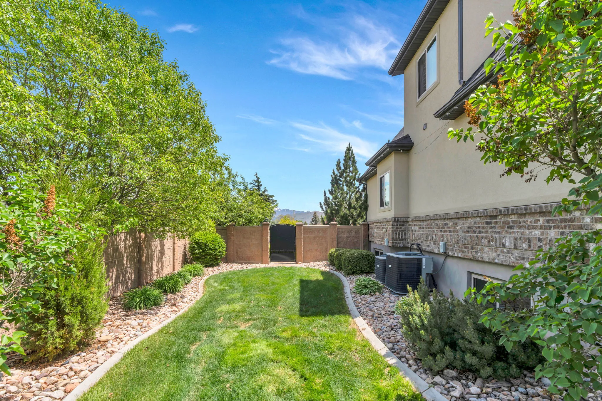 Expansive lawn area bordered by decorative rock landscaping and mature trees