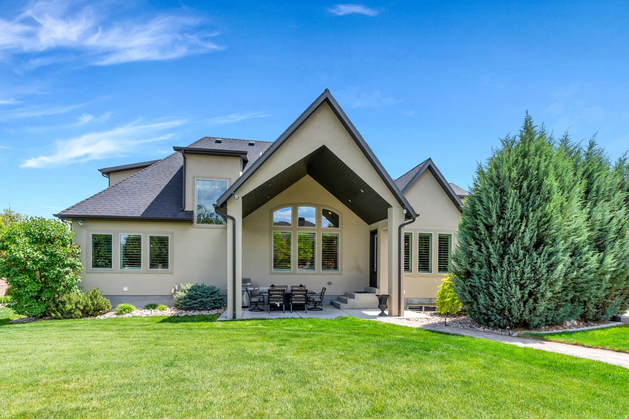 Expansive green lawn bordering a stucco exterior with a covered patio