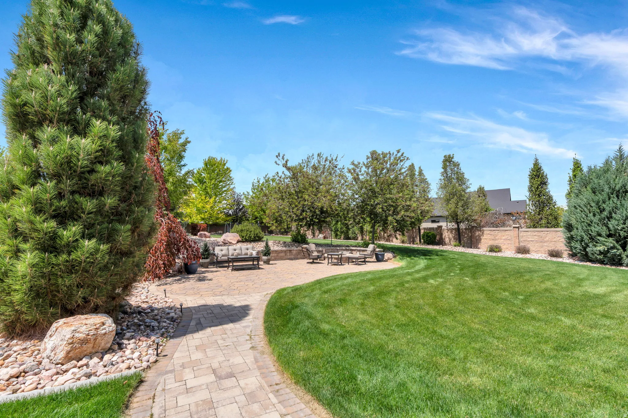 Expansive outdoor living area featuring a paved patio, manicured lawn, and mature landscaping