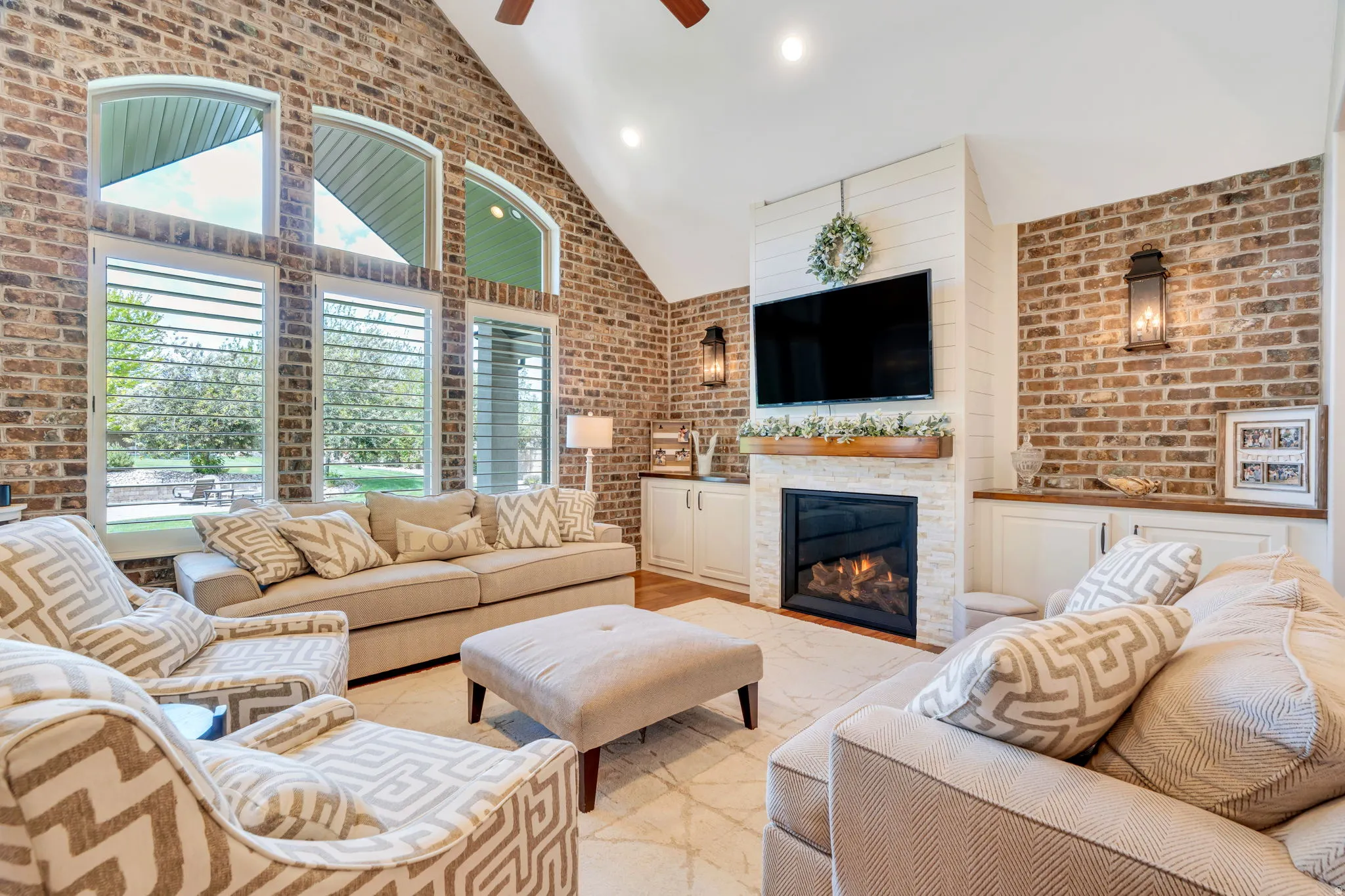 Vaulted living space featuring brick accent walls and a fireplace with a stone surround