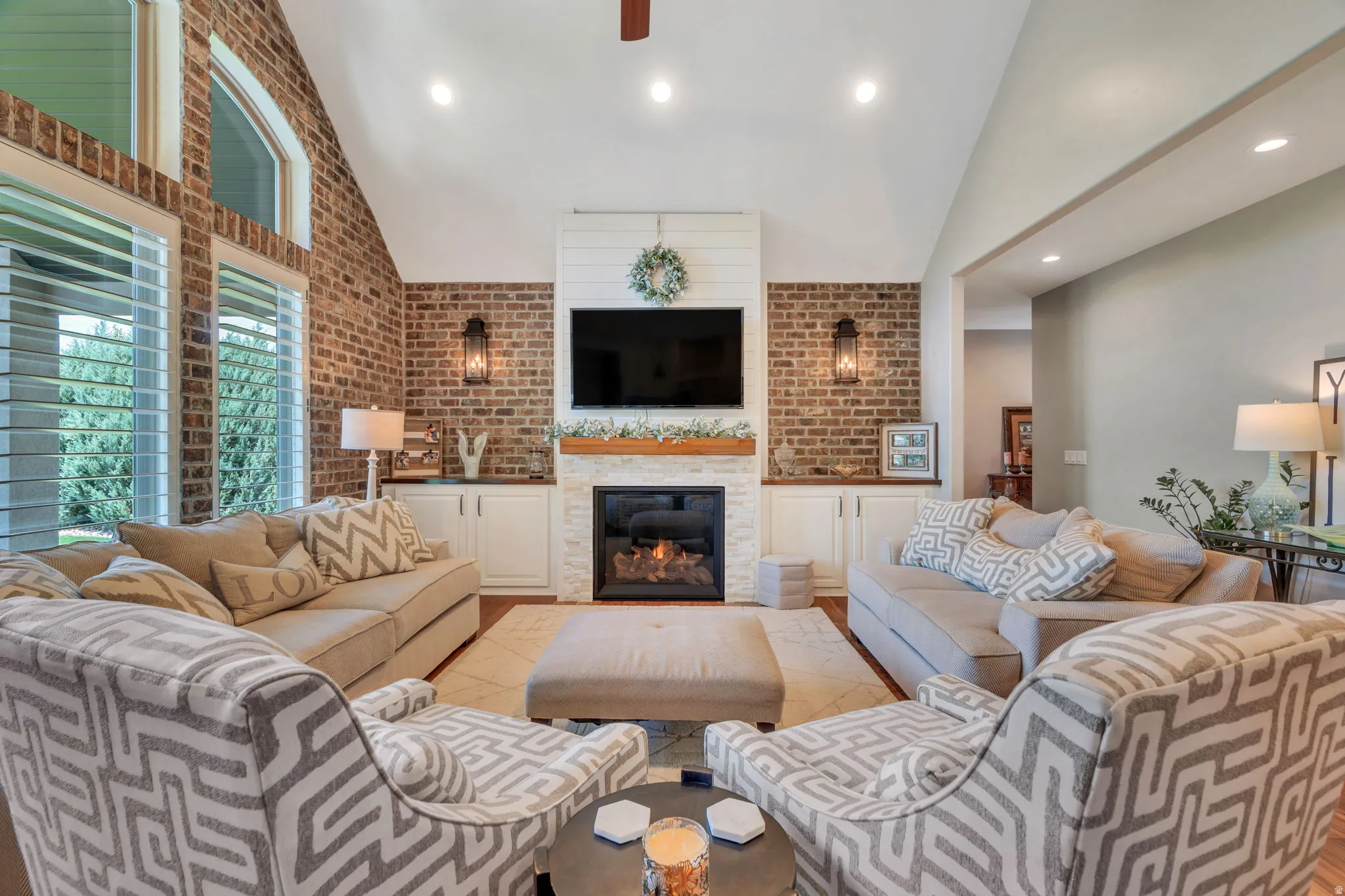 Vaulted ceiling living room featuring an exposed brick accent wall