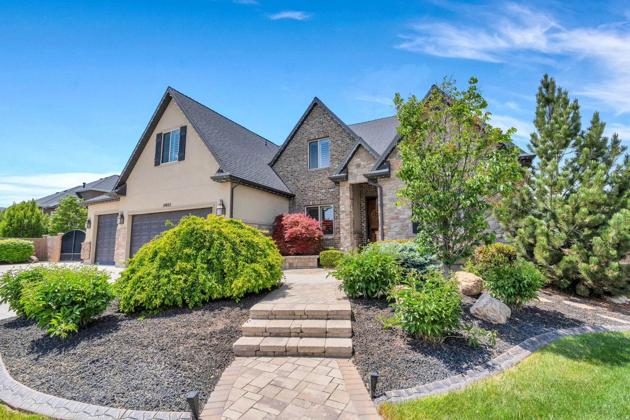 Stone and stucco exterior featuring multiple gables and dark shingle roofing