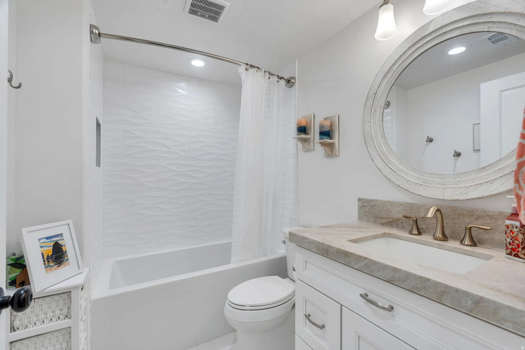 Full bathroom featuring a white vanity with an undermount sink, a stone-finish countertop, and a distressed white oval mirror