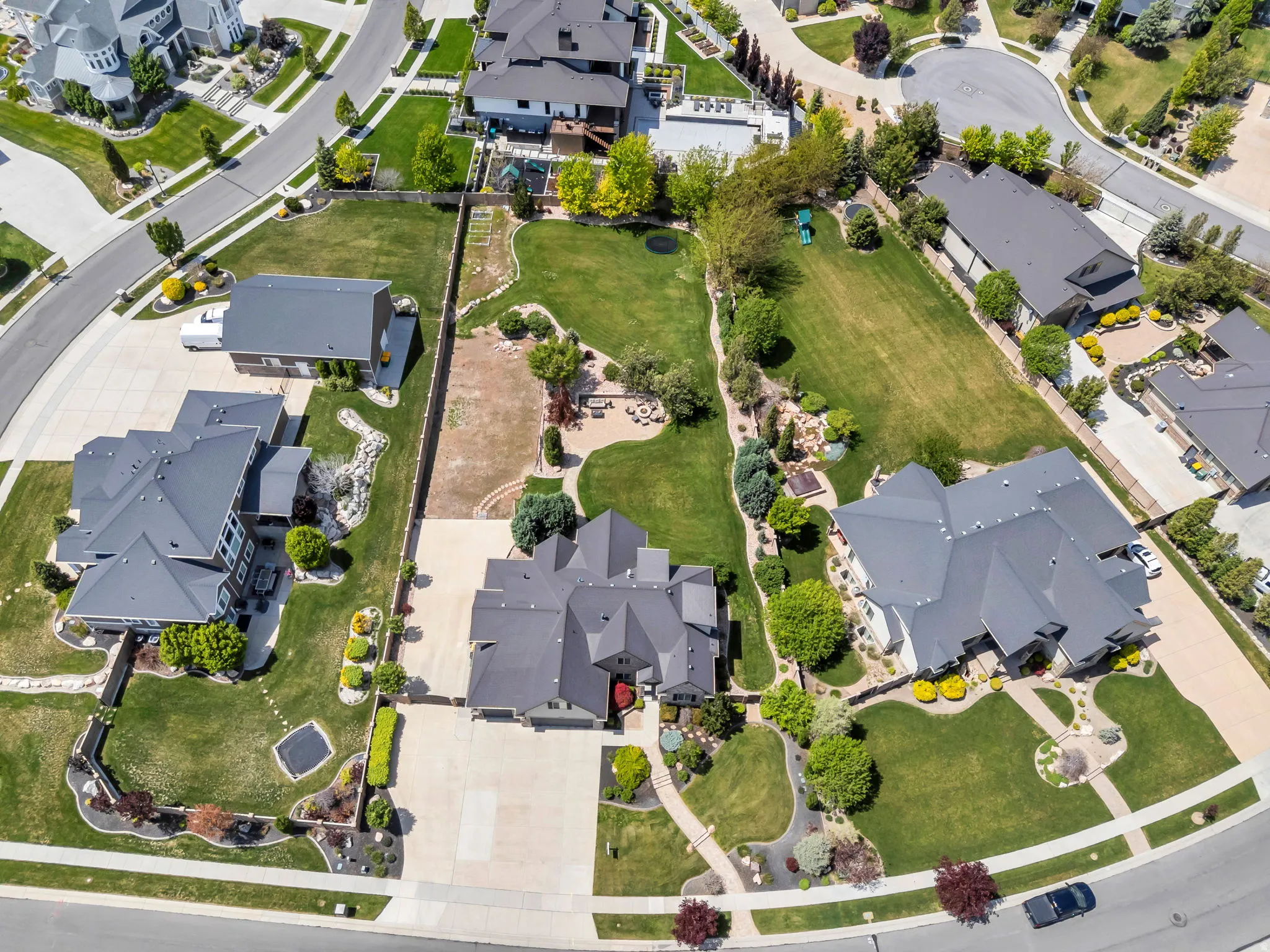 Expansive residential property featuring a large main residence with a multi-gabled roofline and attached garage, surrounded by mature landscaping and a substantial lawn