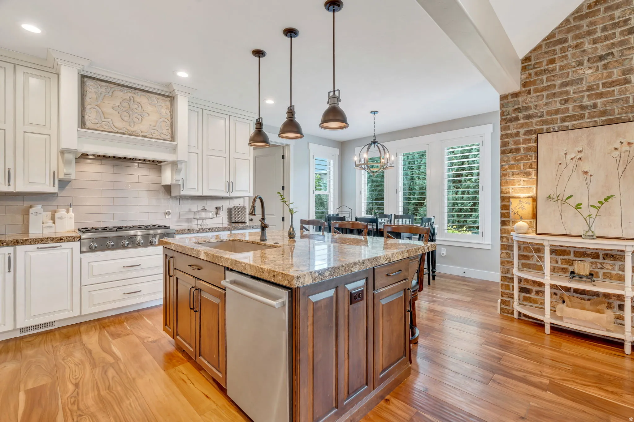 Gourmet kitchen featuring a wood-finish floor, two-tone cabinetry, a large kitchen island with a stone countertop, and a built-in range with a decorative hood