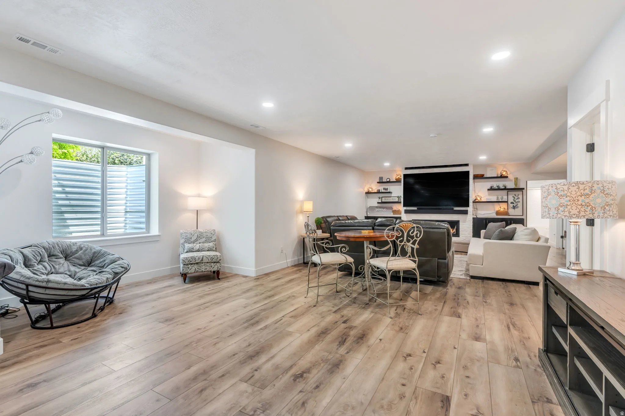 Spacious living area featuring wood-finish flooring, recessed lighting, and a modern fireplace with a built-in television mount