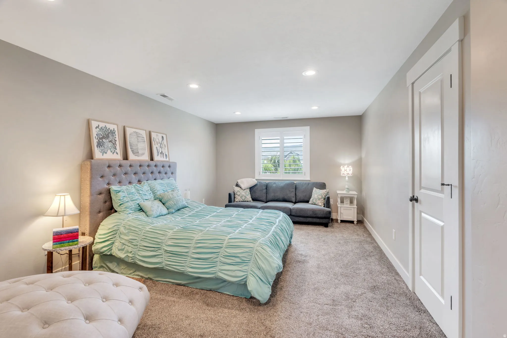 Carpeted room featuring recessed lighting, a window with plantation shutters, a white paneled door, and light gray walls