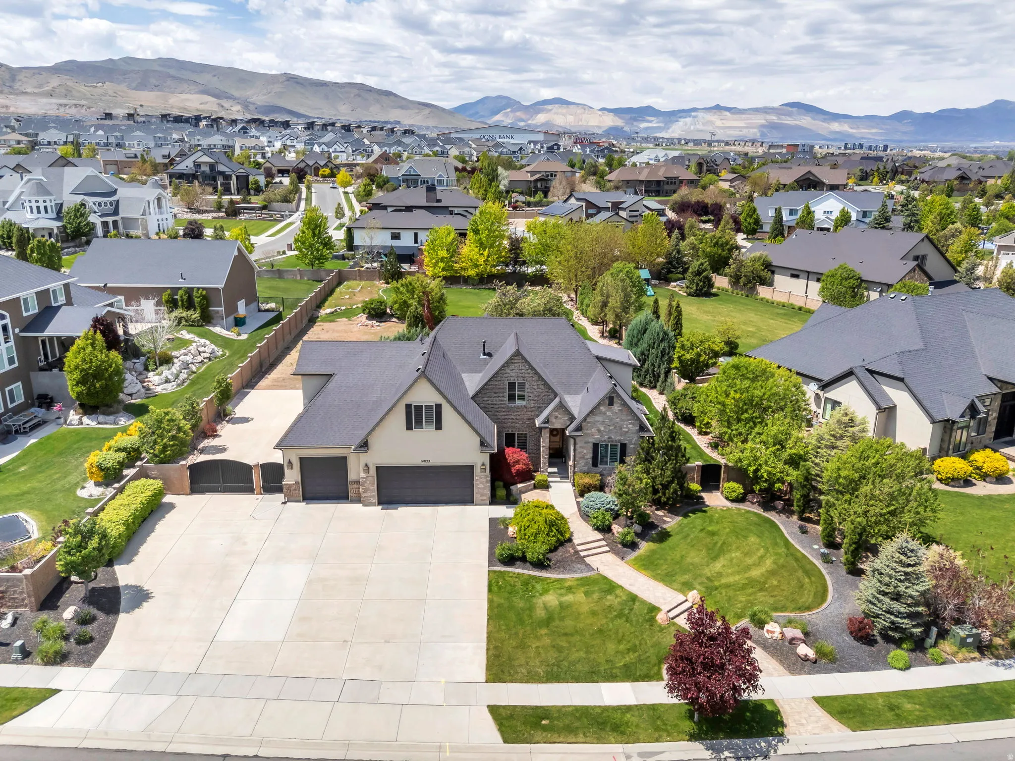 Stone and siding exterior with a multi-car driveway, two-car garage, and mature landscaping