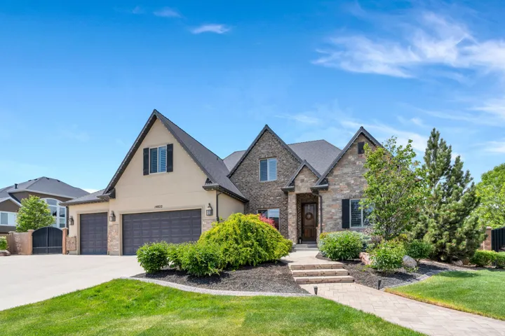 Stone and stucco exterior featuring multiple gables and a dark shingle roof